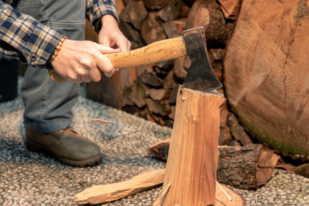Man uses ax to break wood to use for bbq. Preparation of wood to light a fire to cook food on grill outdoor. Close-up of hands holding a cutting tool. Camping, barbecue, outdoors, recreation, conceptの写真素材