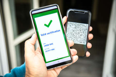 Checking the green pass on smartphone. Required for indoor tables in bar and restaurants, events and to access workplaces and company canteens. Valid certification. Milan, Italy - September 2021の写真素材