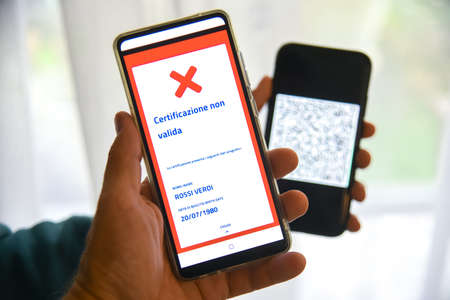 Checking the green pass on smartphone. Required for indoor tables in bar and restaurants, events, workplaces and company canteens. Invalid certification. Access denied. Milan, Italy - September 2021のeditorial素材