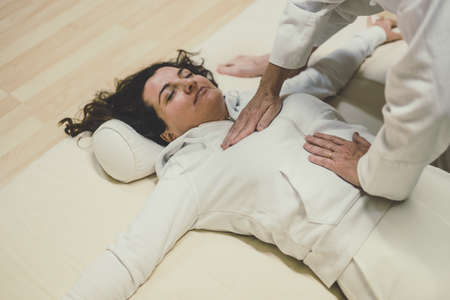 Therapist man doing a Shiatsu massage to a woman. Holistic therapy, treatment with manipulation by thumb, fingers and palms. Wellness, health, relaxation, well-being and alternative medicine concept.の写真素材