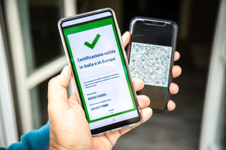 Checking the green pass on smartphone. Required for indoor tables in bar and restaurants, events and to access workplaces and company canteens. Valid certification. Milan, Italy - September 2021のeditorial素材
