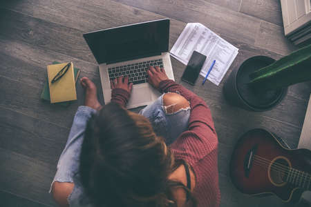 Young woman working on laptop at home. Female hands typing on pc keyboard. Teenager making an Internet video call with remote friends. Girl studying online. Technology, youth, teen, new life conceptの写真素材