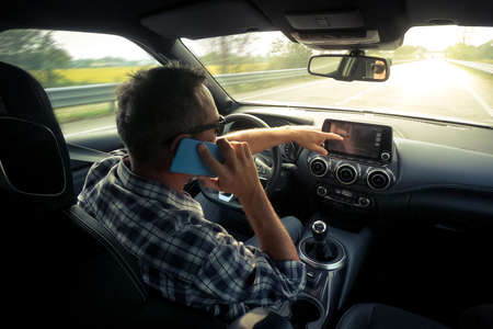 Man drive a car and use infotainment. Driver male reading messages and make phone call while...