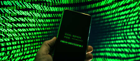 Hand with smartphone doing successful login in a digital network. Display with green numbers in the background. Hacker forced the system. Technology, communication, security, protection, intrusion conceptの写真素材