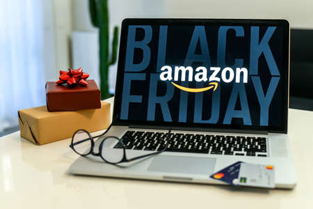 Purchasing Christmas gift in the Amazon online shop the black friday. Logo on the laptop monitor. Purchase of Christmas gifts. E-commerce, tech, online shopping concept. Milan, Italy - November 2021のeditorial素材