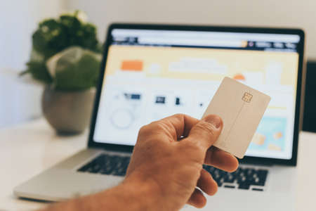 Hand with credit card in front of the laptop monitor doing purchases in an on line shop the black friday Purchase Christmas gifts E-commerce, tech, remote payment, new economy, shopping online conceptの写真素材