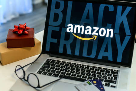 Purchasing Christmas gift in the Amazon online shop the black friday. Logo on the laptop monitor. Purchase of Christmas gifts. E-commerce, tech, online shopping concept. Milan, Italy - November 2021のeditorial素材