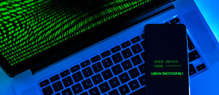 Laptop with green numbers on display. Smartphone displaying successful login with credentials user...