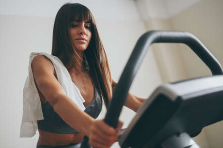 Beautiful girl wipes the sweat after training session. Young sporty woman at the end of the session in the gym. Sweaty athlete with towel ready to take shower. Sport, health, youth and leisure conceptの写真素材