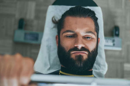 Determined young man working out in the gym. Fit male doing exercise with weights for biceps. Beautiful sporty men. Strong boy lifting the barbell lying on the bench. Wellness, health, sport, concept.の写真素材