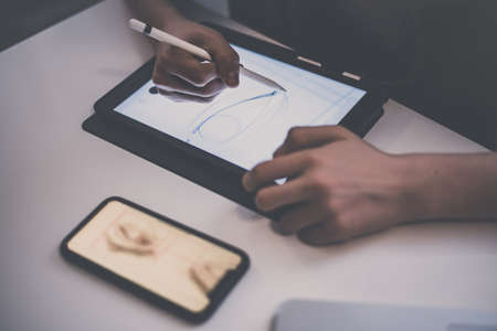 Teenager drawing with tablet and virtual pen. Millennial student doing homework with new technology devices. Young boy draw on pad at home. Male hands working with digital pencil on the touch screen.の写真素材