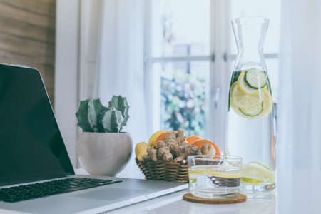 Morning time at home healthy breakfast laptop and drink on table. Natural meal and fruits at work in remote office health nutrition food with computer freelance desktop workspace. Home working conceptの写真素材