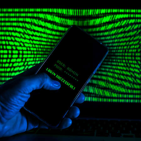 Hand with smartphone doing successful login in a digital network. Display with green numbers in the...