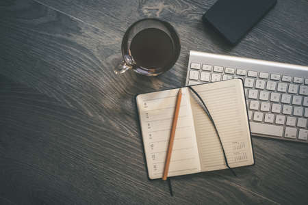 Desktop view with keyboard pencil agenda and technology devices. Table with objects for smart working homeschooling and cup of coffee. Organization, remote work, study, creativity, production concept.の写真素材