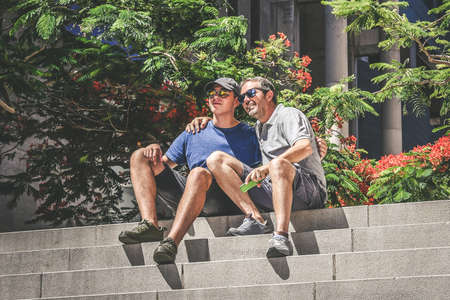 Smiling Father and son talking happy in the city, smartphone in hand. Boy and man enjoying vacation, skyscrapers in metropolis, explore new country. Lifestyle travel and vacation, togetherness conceptの写真素材