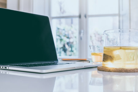 Morning time at home healthy breakfast laptop and cup of lemon tea on table. Natural meal at work in...