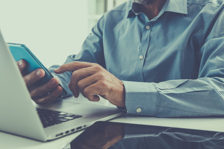 Closeup man hands using smartphone, laptop and tablet. Businessman works with computer, phone, pad
