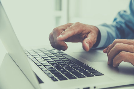 Closeup man hands typing on computer keyboard. Businessman using laptop at home. Office workplaceの写真素材