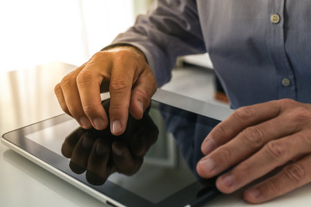 Closeup man hands typing on tablet screen. Businessman using digital pad at home. Office workplaceの写真素材