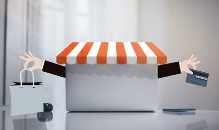 Laptop on white desk. Graphics with credit card and shopping bag in hands. Online e-commerce conceptの写真素材