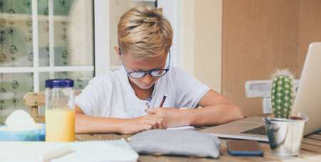 Student doing homework. Boy writing, drawing sitting at the table. School, youth, education concept.の写真素材