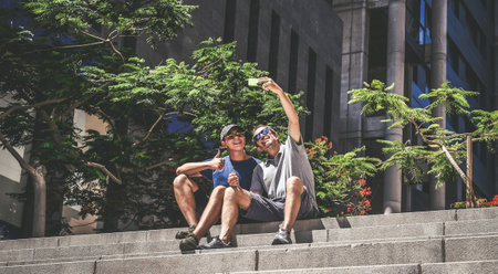 Father and son using smartphone together. Smiling people taking selfie. Boy and man enjoying video call with friends on mobile phone. Technology, lifestyle, communication, travel and vacation conceptの写真素材