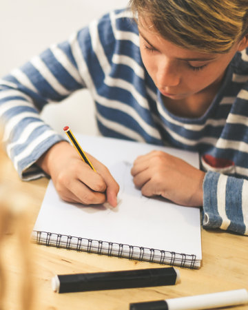 Student drawing with pencil a human figure be inspired by a wooden model. Boy copying a dummy for school art tasks. Kid hold a pencil and draw a manga at home. Education, talent and ability concept.の写真素材