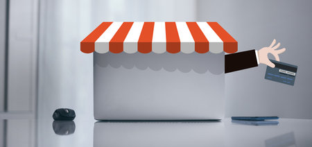 Laptop on white desk. Graphics with credit card in hand. Online shopping and e-commerce concept