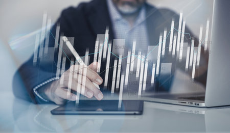 Businessman using laptop and tablet analyzing economic data and sales growth on financial charts
