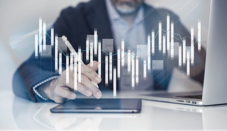 Businessman using laptop and tablet analyzing economic data and sales growth on financial charts