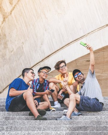 Teenagers and father using smartphone together. Smiling teens taking selfie. Boys enjoying video...
