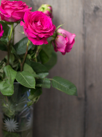 Large pink roses in a crystal vase on a wooden backgroundの写真素材