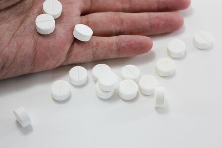 Overdosing on medication, suicide and death, hand surrounded by many pills.