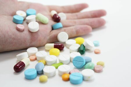 Overdosing on medication, suicide and death, hand surrounded by many pills.