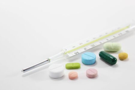 Various colorful medicine drugs, pills, capsules, tablets with mercury thermometer on white background.の写真素材
