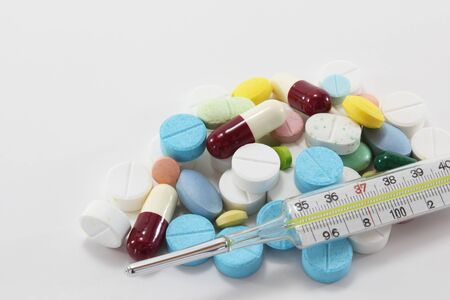 Various colorful medicine drugs, pills, capsules, tablets with mercury thermometer on white background. Close-up view.の写真素材