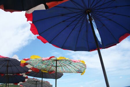 Colorful umbrella on the beach with blue sky and fluffy clouds background, holiday in Thailandの写真素材