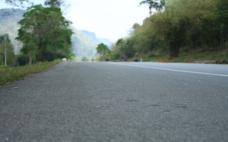 Selective focus of road surface in Thailand with blur mountain and forest backgroundの写真素材