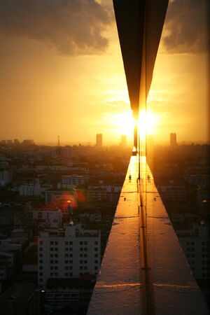 Sunset in the city of Bangkok, Thailand, the real and reflection picture in the mirror of a buildingの写真素材
