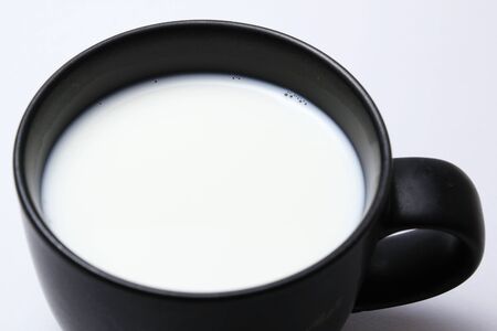 Black cup of hot milk on white backgroundの写真素材