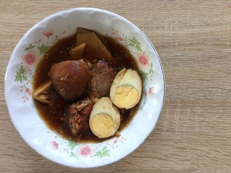 Hard-boiled eggs in the sweet gravy with braised pork also known as Kai Pa Lo, Thai delicious cuisine, top view with wooden backgroundの写真素材