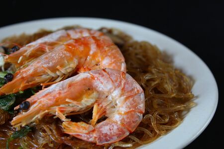 Baked shrimp with vermicelli, Chinese Style Food, close-up view on black backgroundの写真素材