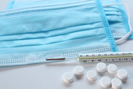 Medical protective mask, mercury thermometer and medicine pills, concept for quarantine, COVID-19, coronavirus, treatment prevention.の写真素材