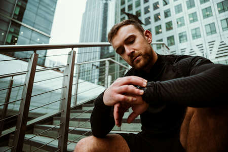 Caucasian male athlete checking activity on smartwatch after long runの写真素材