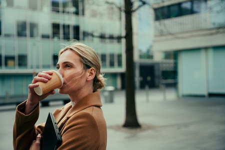 Caucasian business woman drinking hot coffee walking to job interview feeling calm and relaxedの写真素材