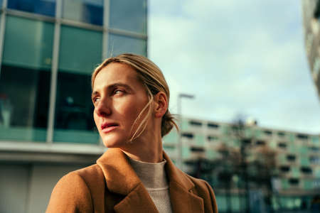 Caucasian blonde business woman looking into the sun prepared for meeting with clientsの写真素材