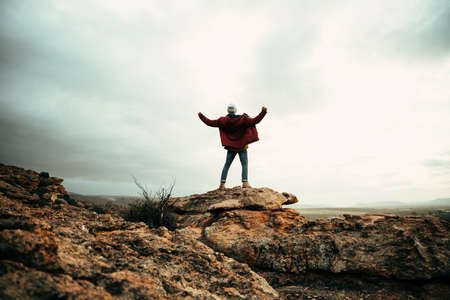 Caucasian male hiker reaching top of mountain peak with open armsの写真素材