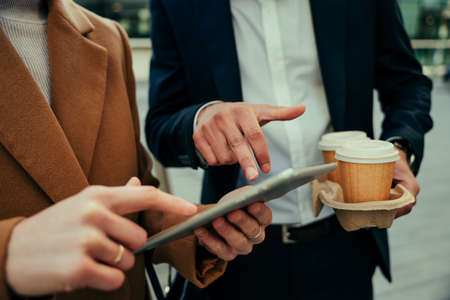 Close up business partners discussing ideas while researching on digital tablet and enjoying coffee before workの写真素材