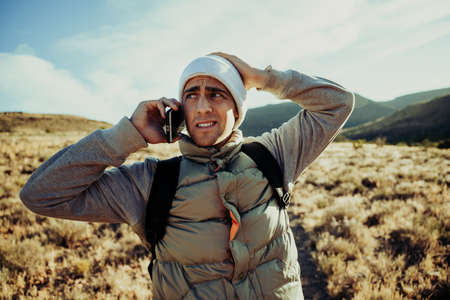 Handsome male active teen calling friends while lost hiking on mountain trailの写真素材