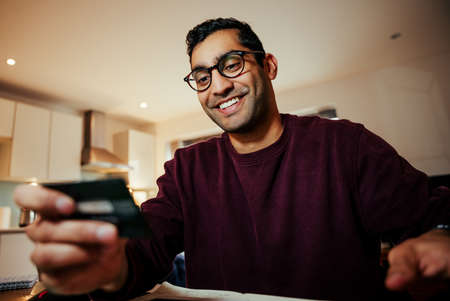 Smiling mixed race business man making online purchase holding credit cardの写真素材